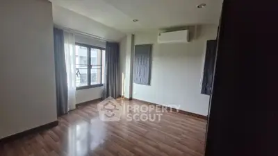 Spacious empty room with wooden flooring and large window