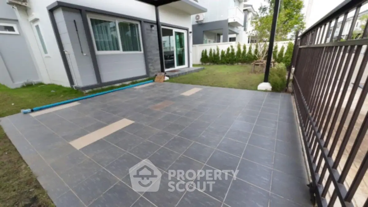 Spacious tiled patio area with modern house exterior and garden view.