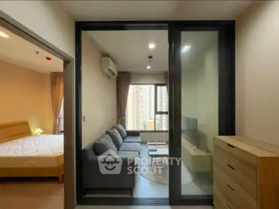 Modern apartment with cozy living room and adjacent bedroom, featuring sleek furniture and large windows.