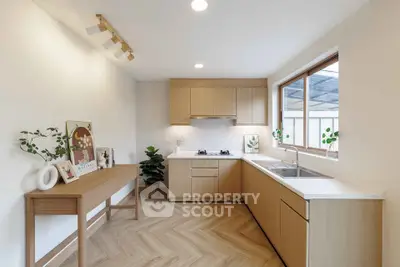 Modern kitchen with wooden cabinets, large window, and stylish decor in a bright, airy space.