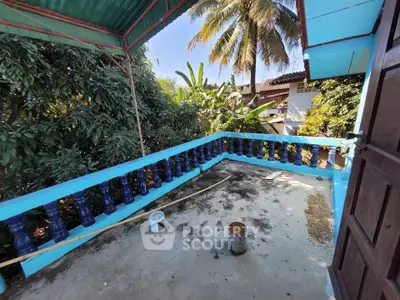 Charming tropical balcony with lush greenery and vibrant blue railing