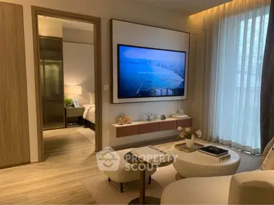 Modern living room with stylish decor and large wall-mounted TV, leading to a cozy bedroom.