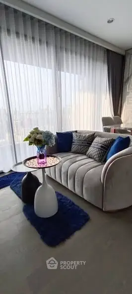 Stylish modern living room with plush sofa and floor-to-ceiling windows offering city views.