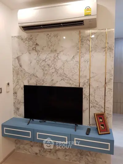 Modern living room with marble accent wall, mounted TV, and sleek air conditioning unit.