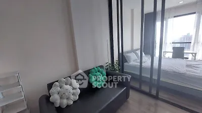Modern studio apartment with cozy living area and bedroom, featuring large windows and stylish decor.