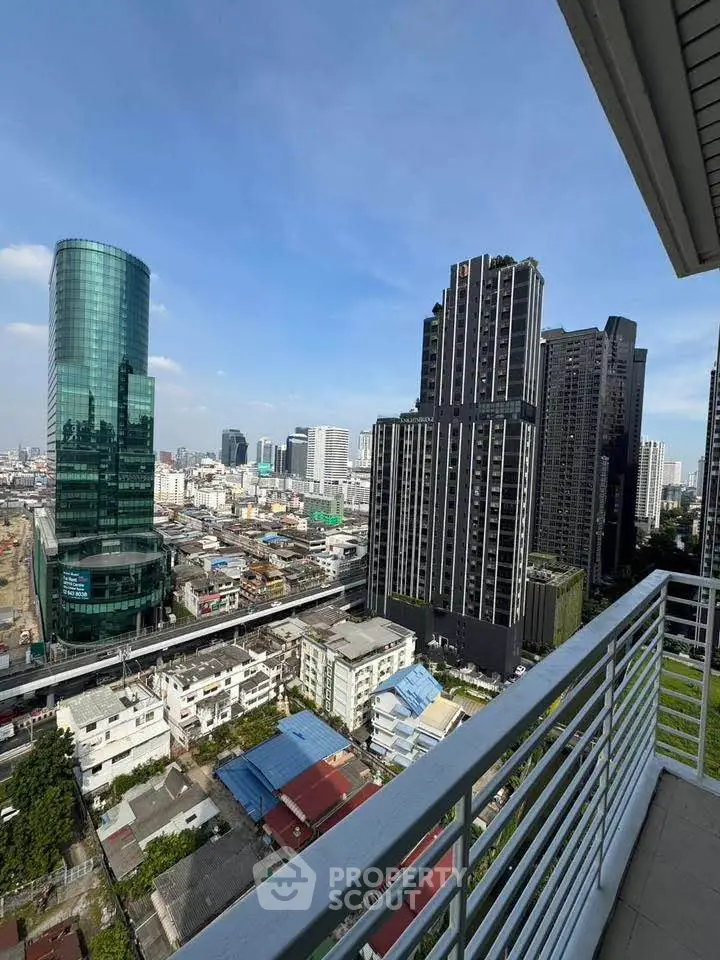 Stunning cityscape view from a high-rise balcony with modern skyscrapers and clear blue sky.