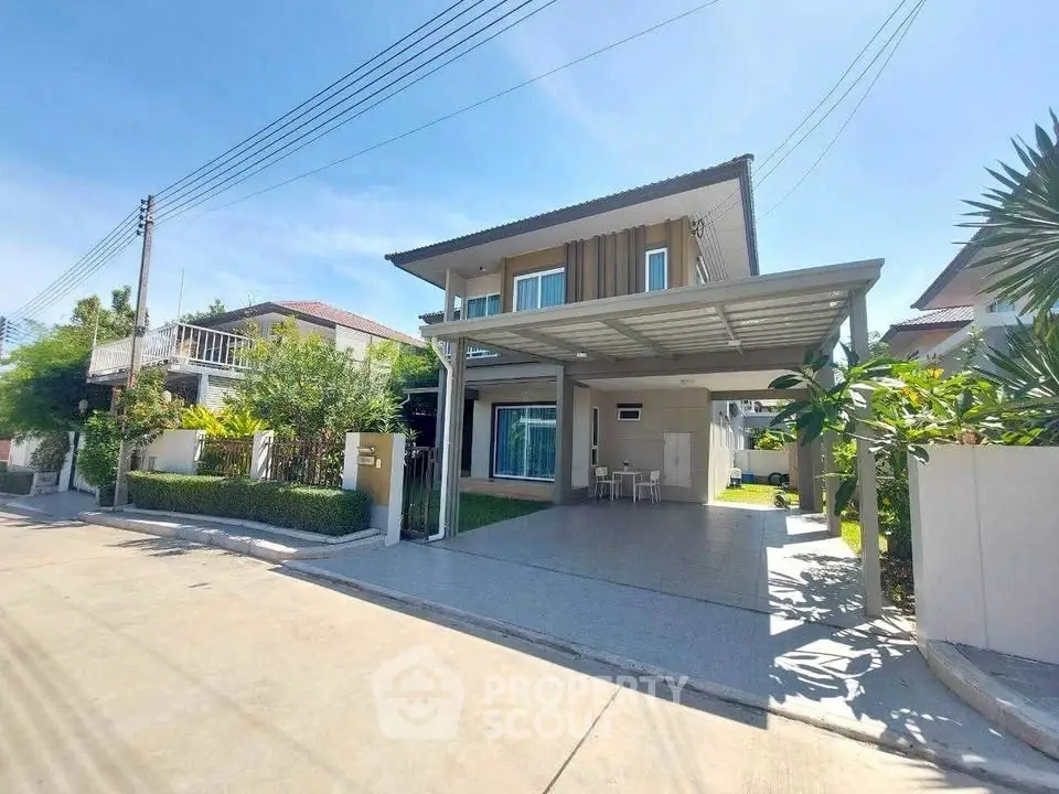 Modern two-story house with carport and lush garden in a serene neighborhood.