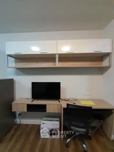 Modern study room with sleek desk, wall-mounted cabinets, and flat-screen TV