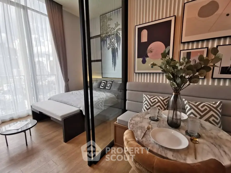 Stylish modern studio with elegant decor and floor-to-ceiling windows offering city views.