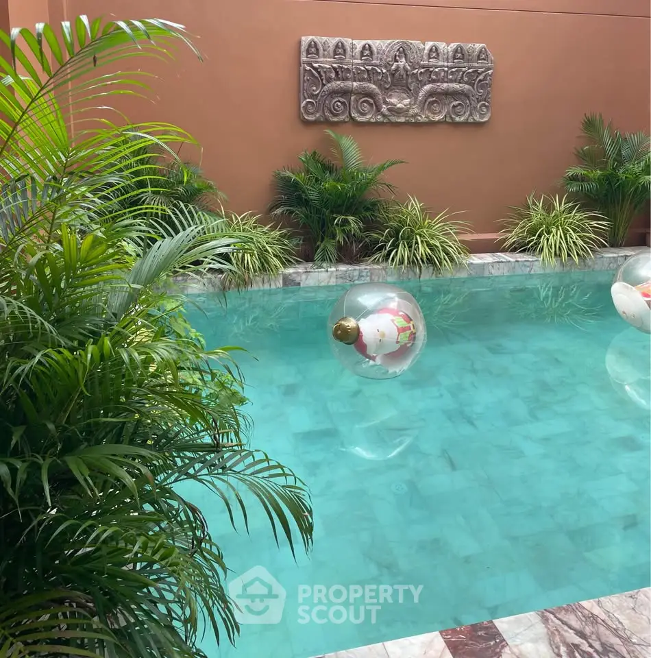 Luxurious private pool with lush greenery and elegant wall decor, perfect for relaxation and entertainment.
