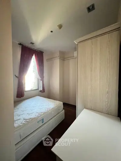 Cozy bedroom with natural light and elegant curtains, featuring a comfortable mattress and wooden furniture.