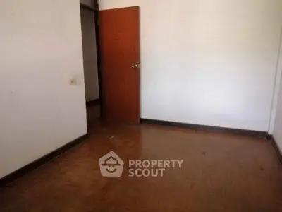Spacious empty room with wooden flooring and open door, ready for customization.
