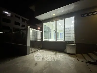 Modern building exterior with illuminated windows at night, showcasing secure gated entrance.