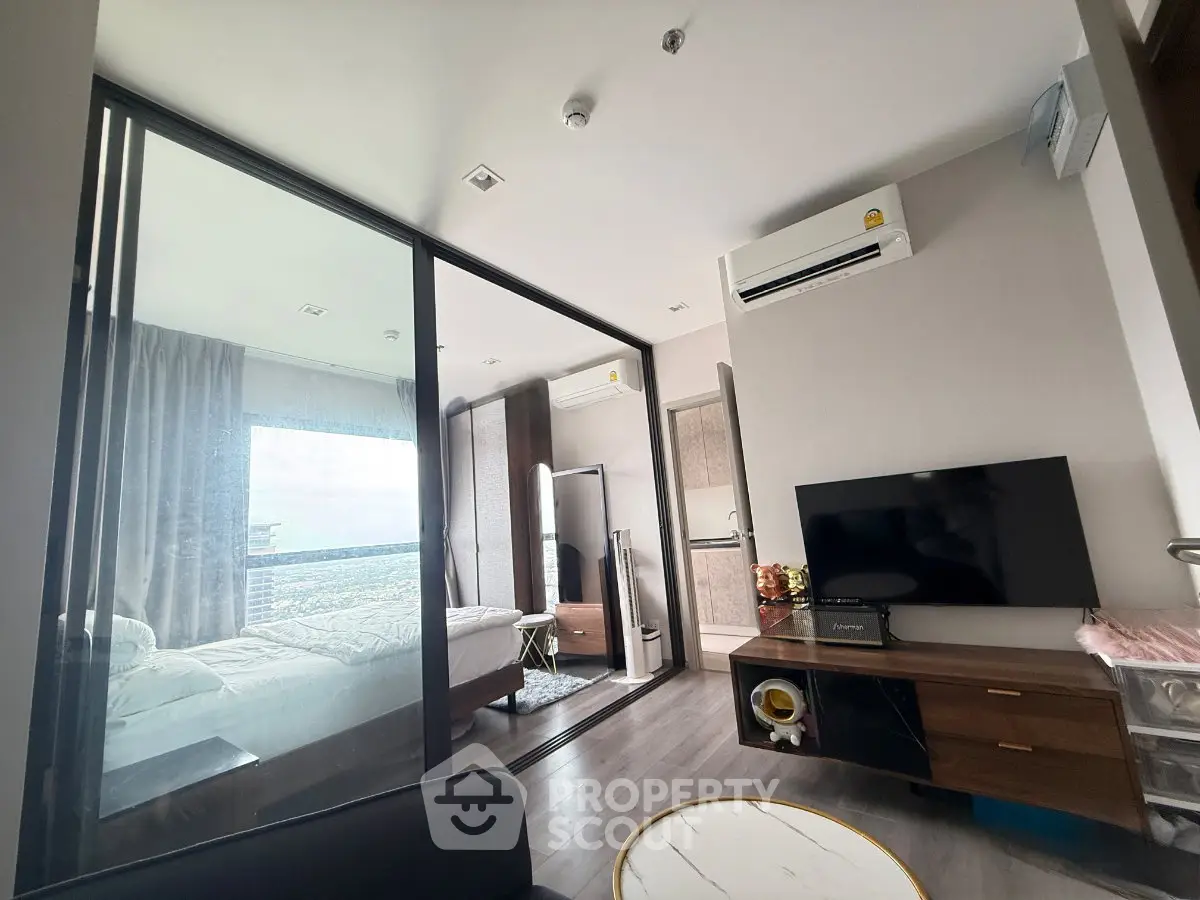 Modern apartment interior with glass partition, cozy bedroom, and stylish living area featuring a TV and air conditioning.