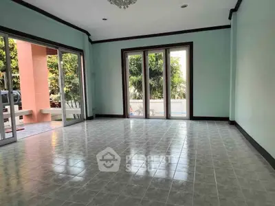 Spacious living room with large windows and garden view, perfect for family gatherings.