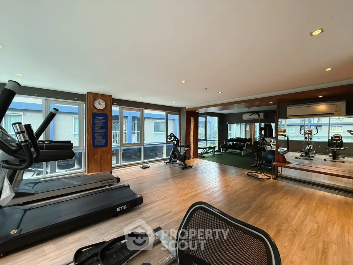 Spacious modern gym with large windows and fitness equipment in a luxury building.