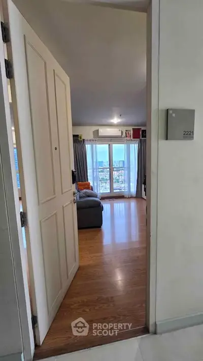 Spacious living room with wooden flooring and large windows offering stunning city views.
