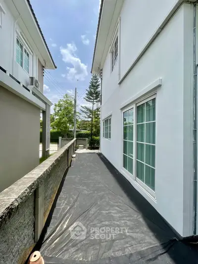 Modern white building exterior with large windows and a sunny outdoor pathway.