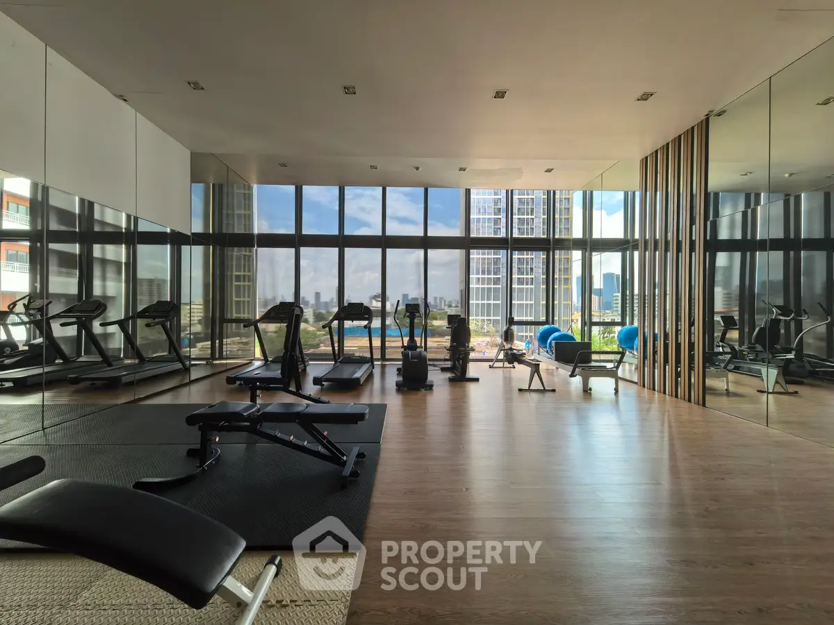 Luxurious gym with city view and modern equipment in high-rise building.