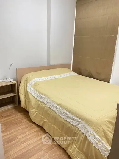 Cozy bedroom with wooden flooring and elegant bedding in a modern apartment.
