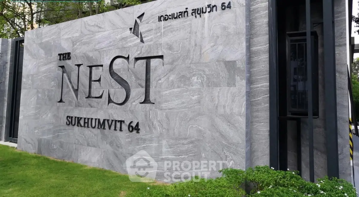 Elegant entrance sign of The Nest Sukhumvit 64 with modern design and lush greenery.