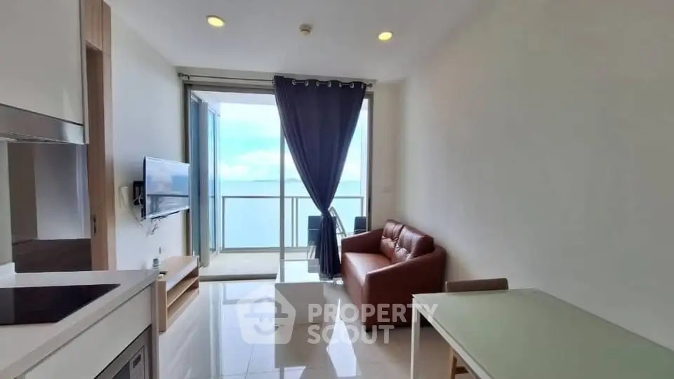 Modern living room with ocean view, featuring sleek furniture and floor-to-ceiling windows.