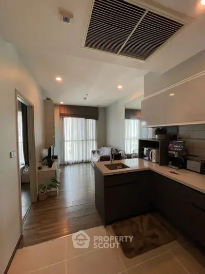 Modern open-layout kitchen with sleek appliances and cozy living area in a stylish apartment.