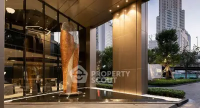 Luxurious modern building entrance with elegant sculpture and cityscape view.