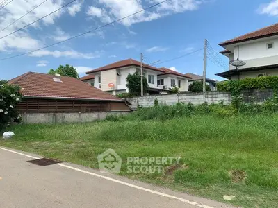 Spacious residential plot with lush greenery and modern houses in a serene neighborhood.