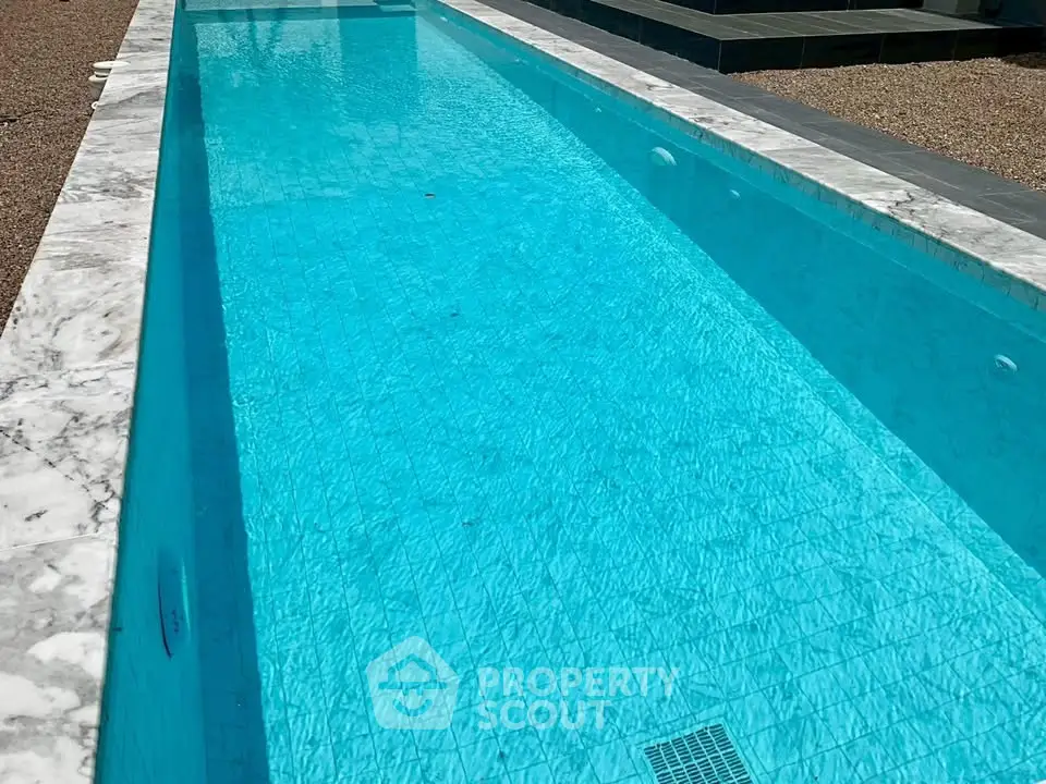 Luxurious marble-lined swimming pool with crystal clear water, perfect for relaxation and leisure.