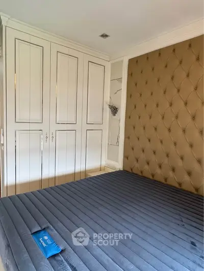 Luxurious bedroom with tufted wall and built-in wardrobe, perfect for modern living.