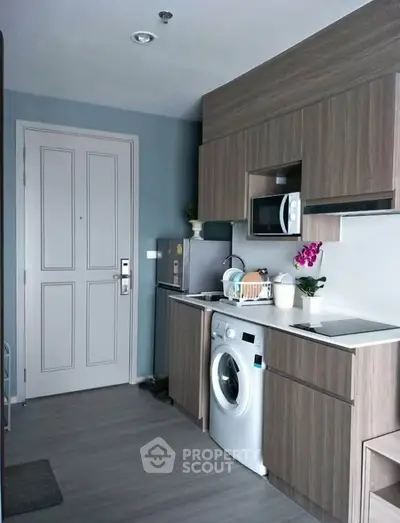 Modern kitchen with washing machine and microwave in compact apartment