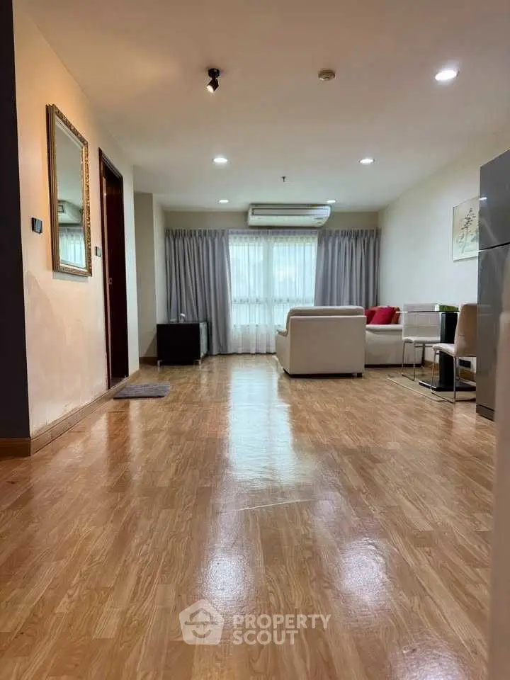 Spacious living room with wooden flooring and modern furniture, perfect for relaxation and entertainment.