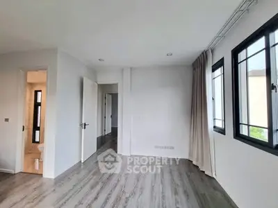 Spacious bedroom with modern flooring and large windows in a bright apartment.