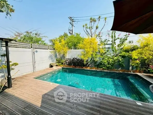 Luxurious private pool with wooden deck surrounded by lush greenery, perfect for relaxation and entertainment.