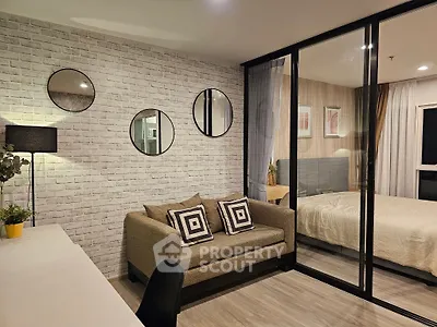 Modern living room with stylish decor and cozy bedroom view through glass partition.