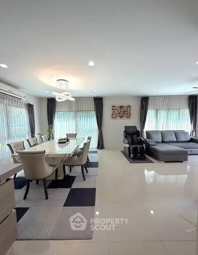Spacious modern living room with elegant dining area and massage chair, featuring large windows and stylish decor.