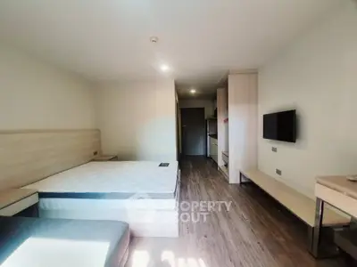 Modern minimalist bedroom with sleek wooden flooring and mounted TV