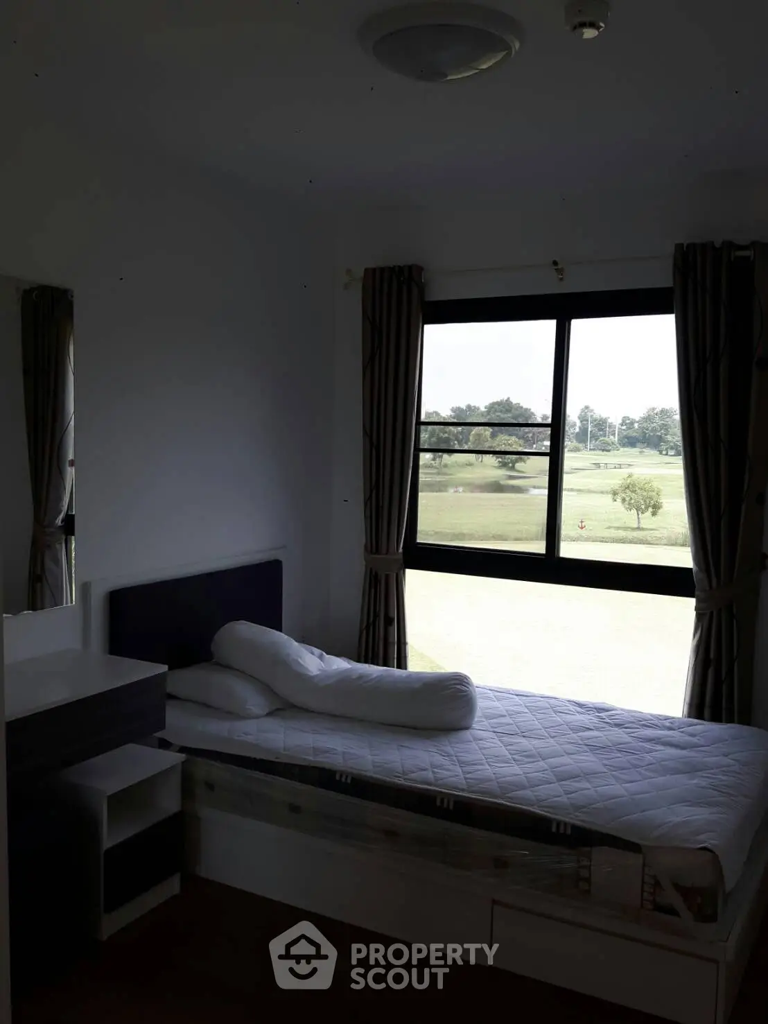 Cozy bedroom with scenic window view overlooking lush greenery, perfect for relaxation.