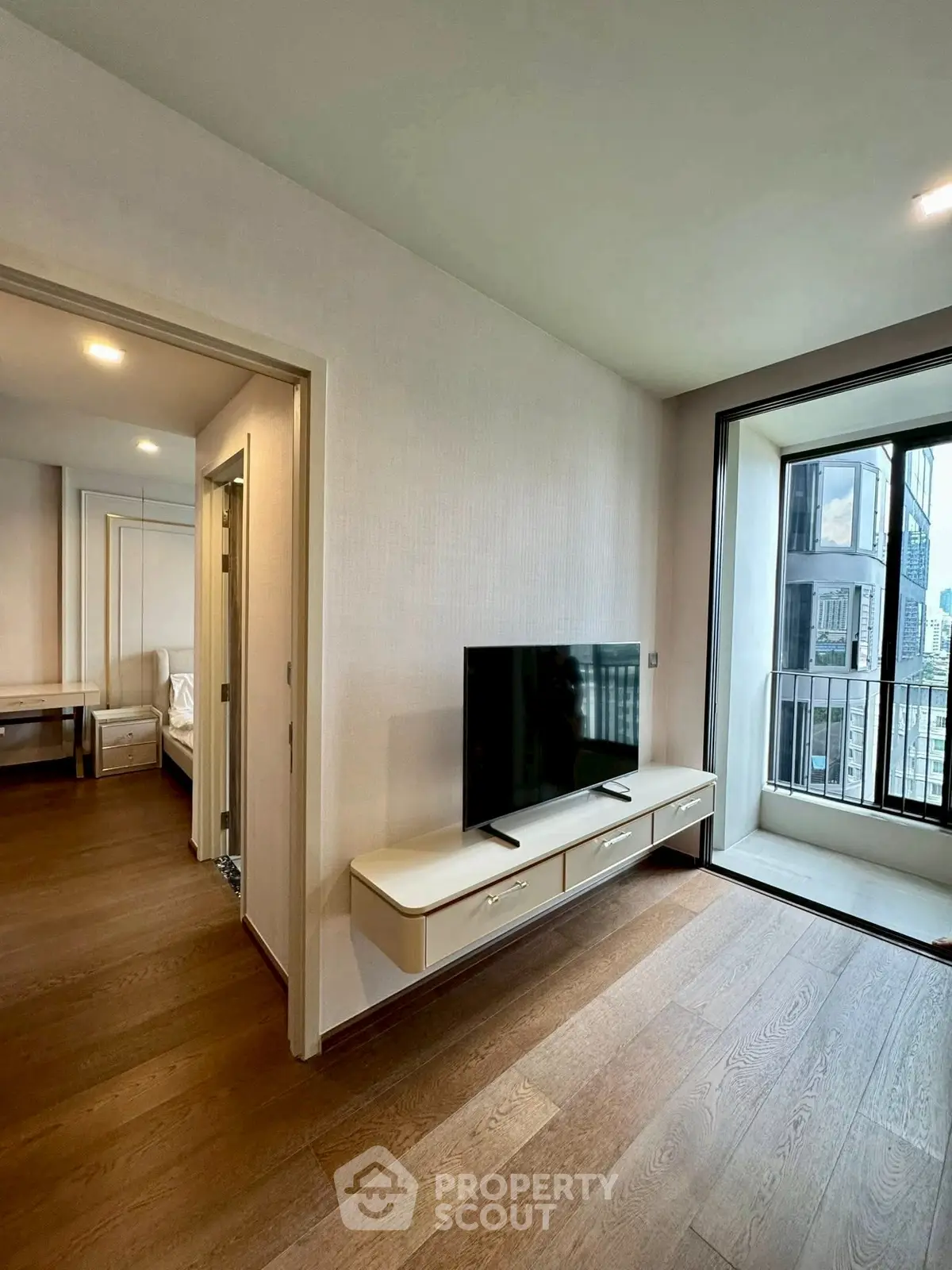 Modern apartment interior with sleek TV setup and balcony view