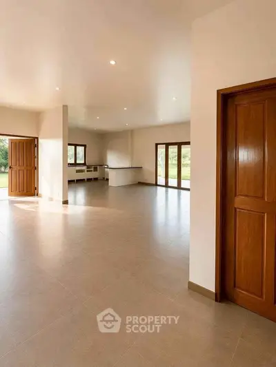 Spacious open-plan living room with large windows and natural light, perfect for modern living.
