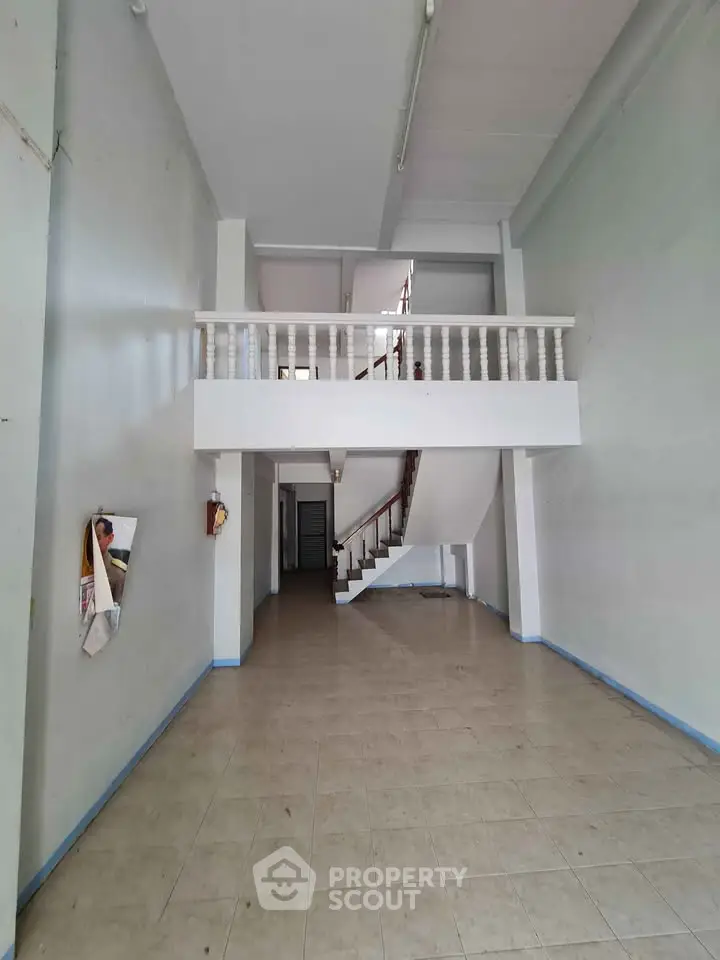 Spacious two-story interior with mezzanine and tiled flooring, ideal for versatile use.
