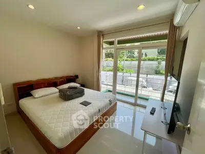 Spacious bedroom with pool view and modern amenities in a serene setting.
