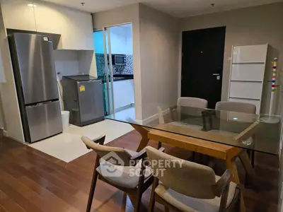 Modern dining area with glass table and kitchen appliances in open layout