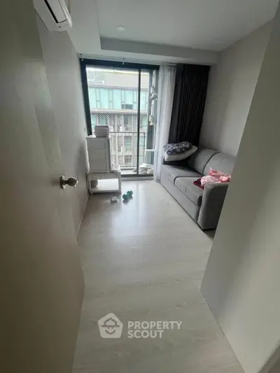 Cozy small living room with a sofa and large window in a modern apartment.