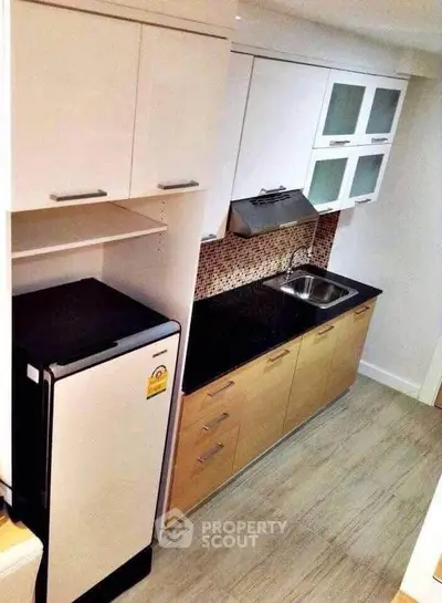 Modern kitchen with sleek cabinetry and compact design, featuring a stylish backsplash and efficient layout.