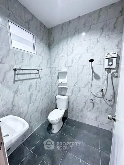 Modern bathroom with sleek gray tiles and essential fixtures in a real estate property.