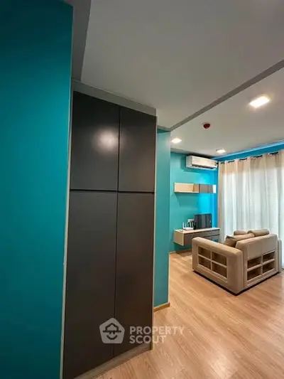 Modern living room with teal walls, cozy sofa, and sleek storage unit.