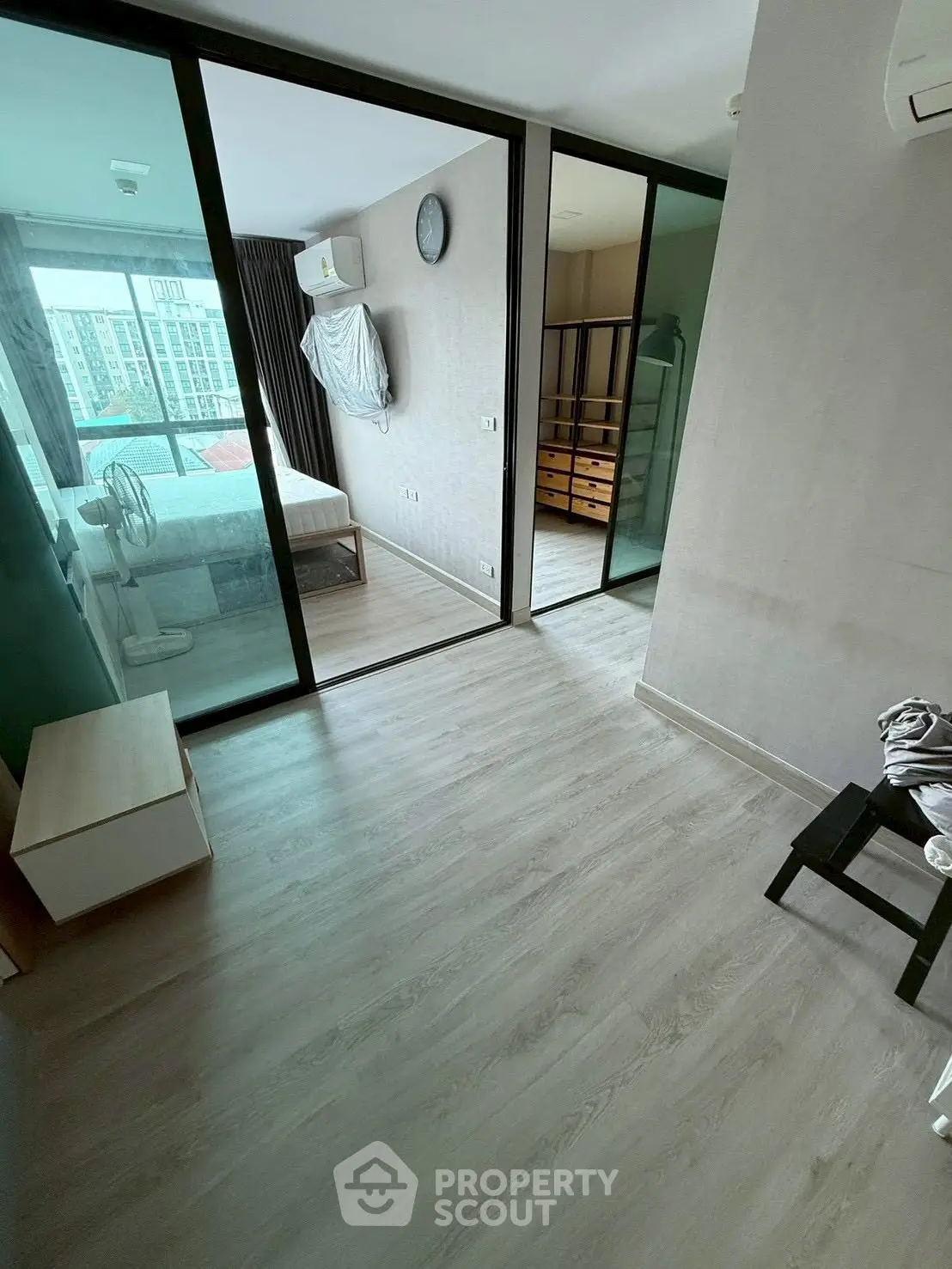 Modern bedroom with sliding glass doors and wooden flooring in a stylish apartment.