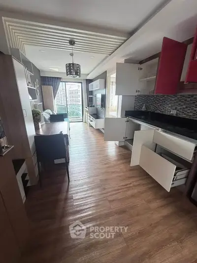 Modern open-layout kitchen and living room with wooden flooring and balcony view.